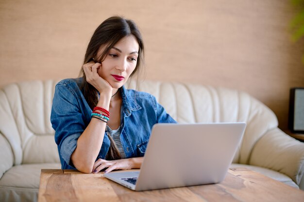 Piękna młoda kobieta patrzeje laptopu ekran