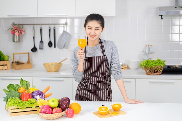 Piękna młoda kobieta pije świeży sok pomarańczowy w kuchni. zdrowa dieta