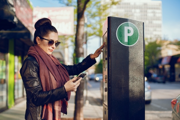 piękna młoda kobieta płaci za parkowanie w metrach na ulicy