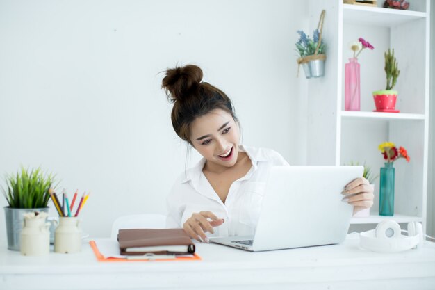 Piękna młoda kobieta pracuje na jej laptopie w jej pokoju.