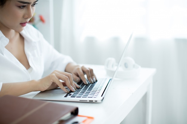 Piękna młoda kobieta pracuje na jej laptopie w jej pokoju.