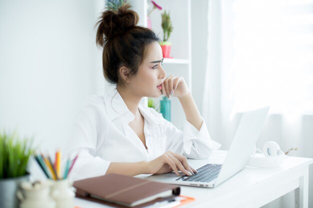 Piękna młoda kobieta pracuje na jej laptopie w jej pokoju.