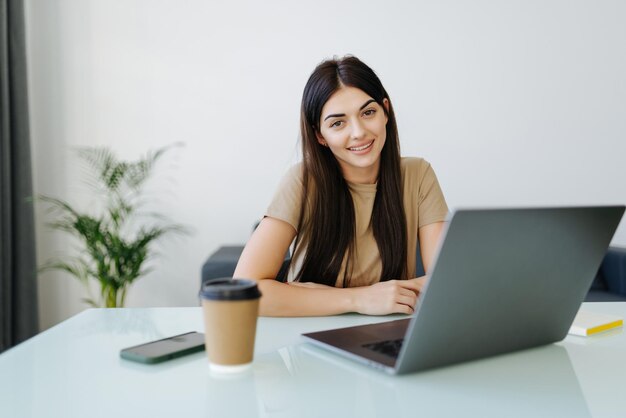 Piękna młoda kobieta pracuje na laptopie w swoim biurze w domu