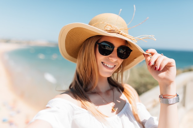 Piękna młoda kobieta robi selfie na plaży nad oceanem