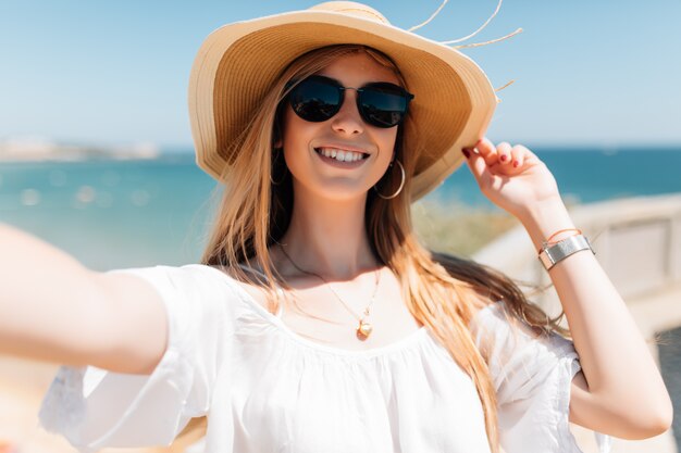 Piękna młoda kobieta robi selfie na plaży nad oceanem