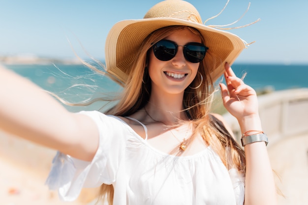 Piękna młoda kobieta robi selfie na plaży nad oceanem