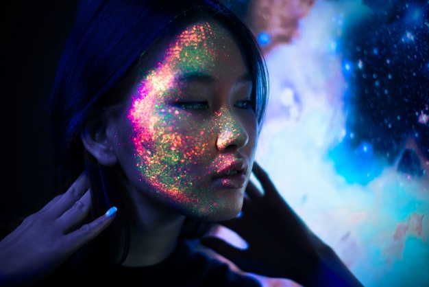 Piękna Młoda Kobieta Tańczy I Robi Imprezie Z Fluorescencyjnym Obrazem Na Twarzy. Neonowe Portrety Twarzy Premium Zdjęcia