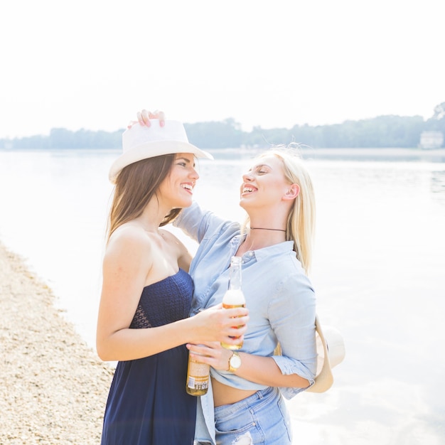 Piękna młoda kobieta trzyma piwną butelkę stoi blisko plaży