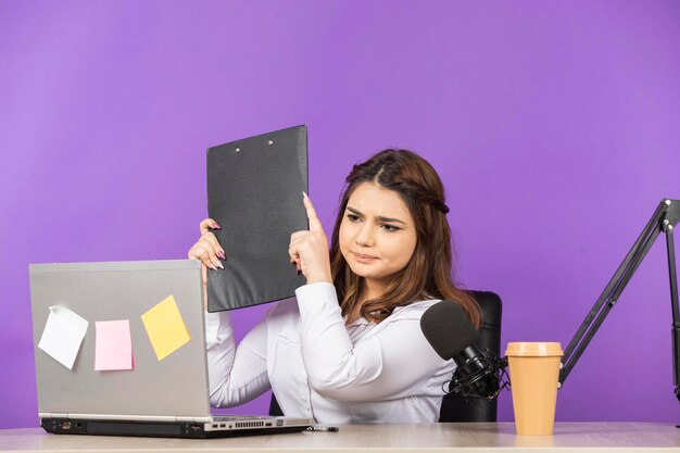 Piękna młoda kobieta trzymająca notatnik i patrząca na ekran komputera Wysokiej jakości zdjęcie