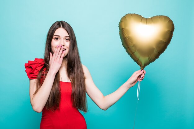Piękna młoda kobieta w czerwonej sukience z balonem w kształcie serca. Kobieta na Walentynki. Symbol miłości