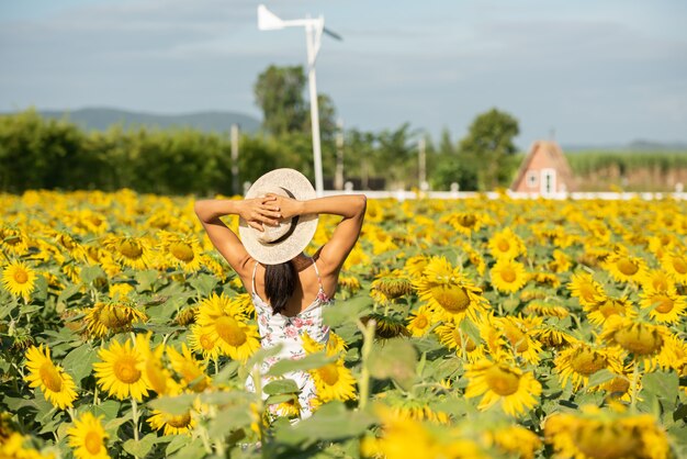 Piękna młoda kobieta w polu słoneczników w białej sukni. podróż na koncepcji weekendu. portret autentycznej kobiety w słomkowym kapeluszu. Na zewnątrz na polu słonecznika.