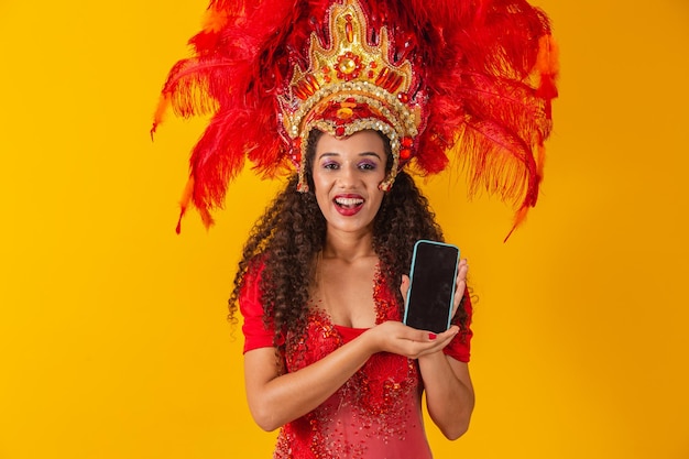 Piękna młoda kobieta w specjalnym karnawałowym stroju pióro trzymając smartfon z pustego ekranu z miejscem na tekst. wirtualny karnawał, promocja i reklamy