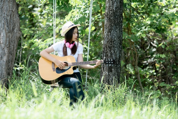 Piękna młoda kobieta z Acustic gitarą przy naturą