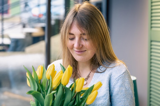 Piękna młoda kobieta z bukietem żółtych tulipanów