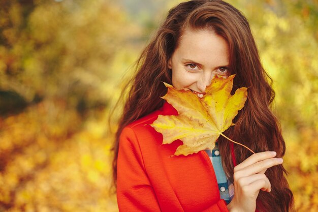 Piękna młoda kobieta z długie falowane włosy obejmujące twarz z liściem