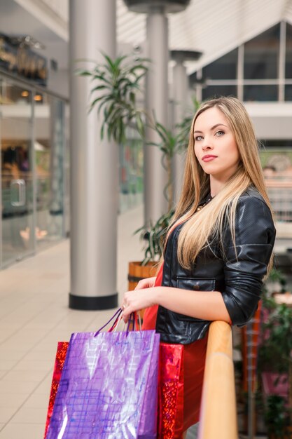 Piękna młoda kobieta z torba na zakupy w centrum handlowym