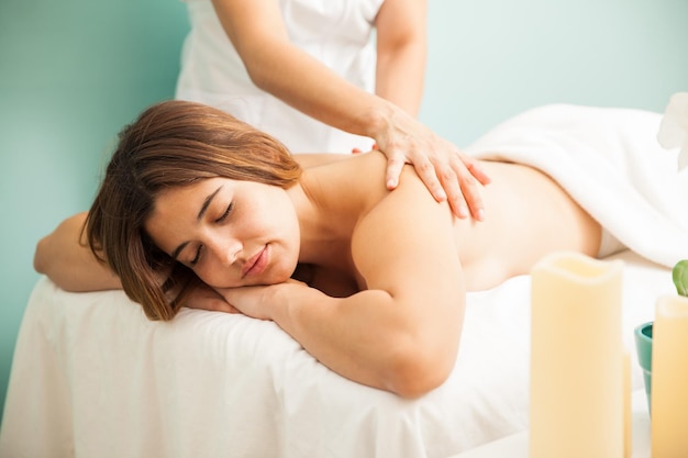 Piękna młoda latynoska kobieta zasypia, gdy masażystka wykonuje bardzo relaksujący masaż w spa