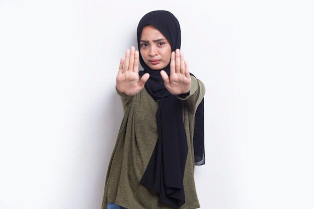 Piękna młoda muzułmanka z otwartą dłonią robi znak stopu z poważnym gestem obrony wyrazu