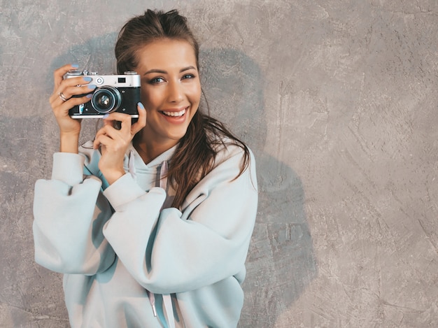 Bezpłatne zdjęcie piękna młoda uśmiechnięta fotograf dziewczyna bierze fotografie używać jej retro kamerę.