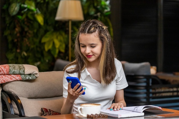 Piękna pani siedzi w restauracji i patrzy na swój telefon