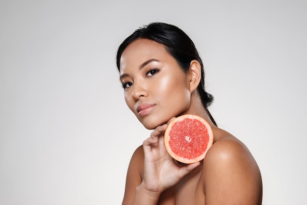 Piękna spokojna kobieta pokazuje grapefruitowego plasterek