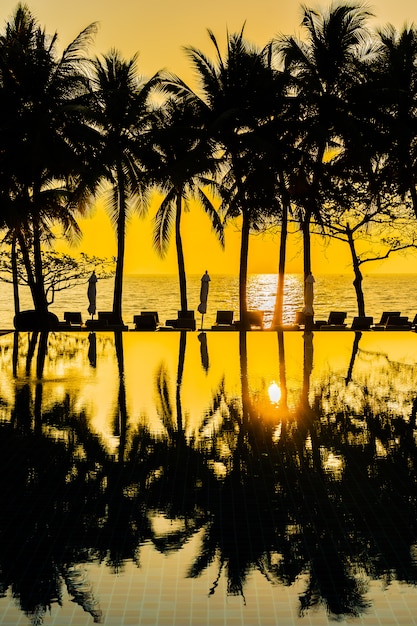 Piękna sylwetka palmy kokosowej na niebie wokół basenu w hotelowym kurorcie blisko oceanu morskiego