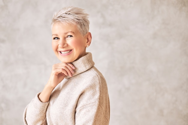 Piękna szczęśliwa kobieta na emeryturze sobie przytulny sweter i krótką fryzurę