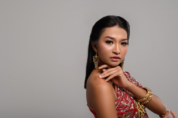 Piękna Tajlandzka kobieta jest ubranym Tajlandzką suknię i patrzeje strona