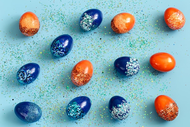 Bezpłatne zdjęcie piękna wielkanocna niebieska z niebiesko-pomarańczowymi ozdobnymi jajkami w cekinami.