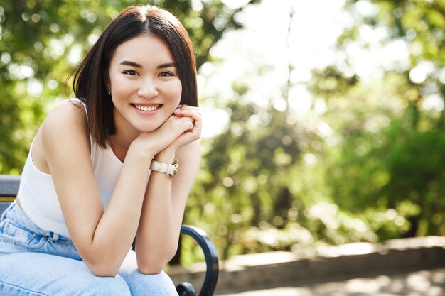Piękne azjatyckie kobiety siedzącej na ławce i uśmiechając się