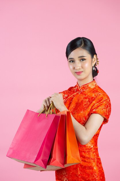 Piękne azjatyckie kobiety szczęśliwy uśmiech i zakupy w chińskim nowym roku na różowym tle.