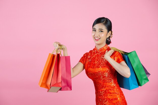 Piękne azjatyckie kobiety szczęśliwy uśmiech i zakupy w chińskim nowym roku na różowym tle.