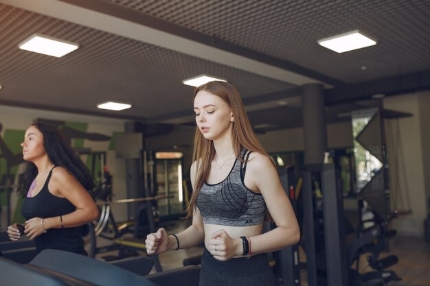 Piękne dziewczyny na siłowni. Sportowe panie w odzieży sportowej. Przyjaciele na torze wyścigowym.