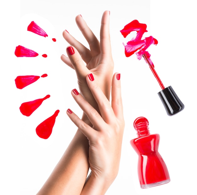 Piękne kobiece dłonie z czerwoną butelką do manicure i paznokci z pędzelkiem