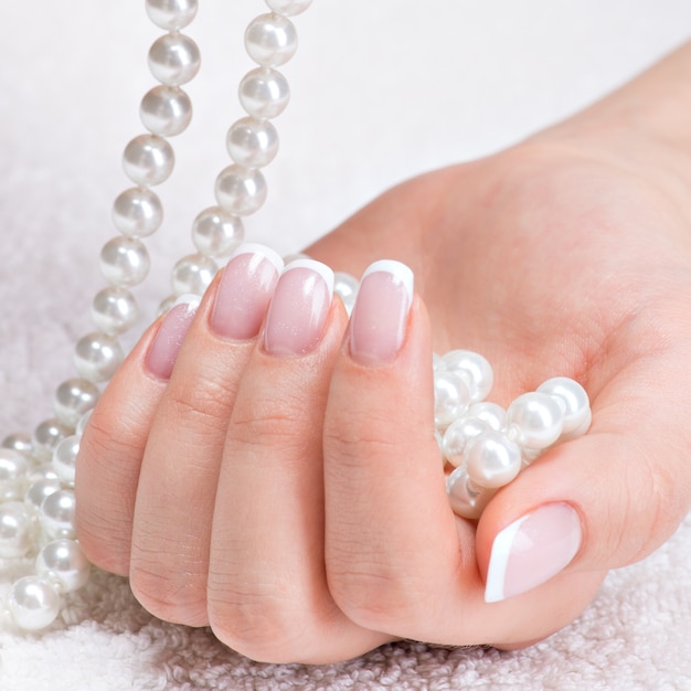 Bezpłatne zdjęcie piękne kobiece paznokcie z pięknym french manicure i białymi perełkami