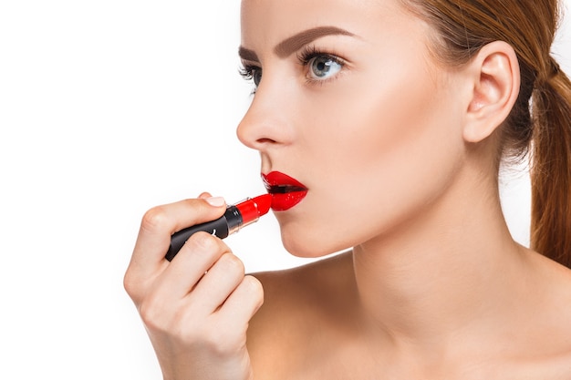 Piękne kobiece usta z makijażem i czerwoną pomadą na białym tle. Proces pracy artysty makijażu