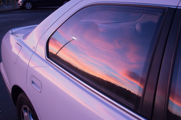 Piękne kolory zachodzącego słońca odbijają się w oknie fioletowego samochodu