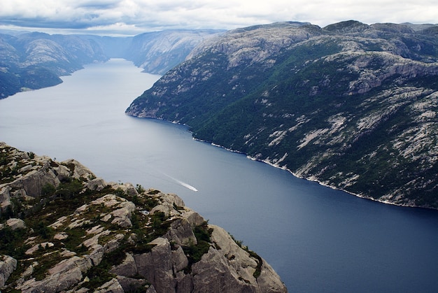 Piękne krajobrazy słynnych klifów Preikestolen w pobliżu jeziora pod zachmurzonym niebem w Stavanger