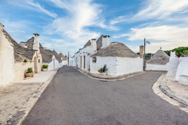 Piękne miasto Alberobello z domami Trulli wśród zielonych roślin i kwiatów, główna dzielnica turystyczna, region Apulia, południowe Włochy. Typowe budynki zbudowane z suchego kamienia i stożkowego dachu