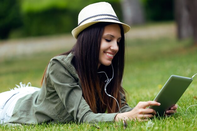Piękne młoda kobieta przy użyciu cyfrowego tabletu w parku.