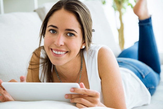 Piękne młoda kobieta przy użyciu jej cyfrowej tabletu w domu.