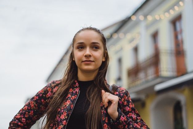 Piękne młodych szczęśliwy brunette Dziewczyna z długimi włosami stwarzających na zewnątrz pomieszczeń. Fotografia uliczna, portret, zbliżenie.