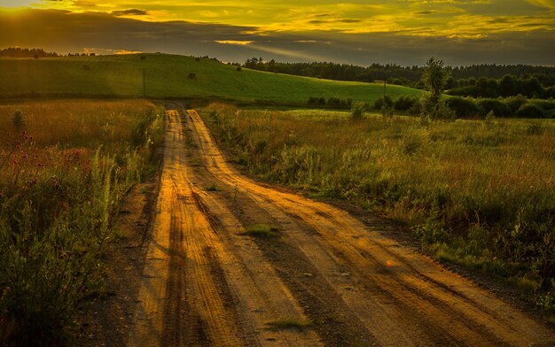 Piękne ujęcie drogi przez pole podczas oszałamiającego zachodu słońca