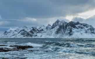 Bezpłatne zdjęcie piękne ujęcie fal morskich na tle zaśnieżonej góry