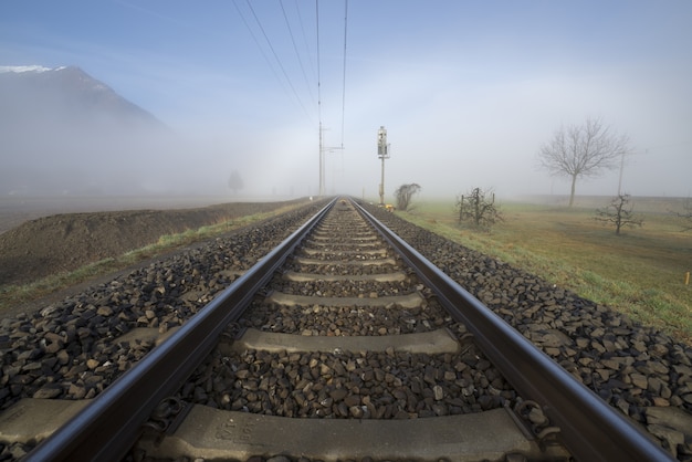 Bezpłatne zdjęcie piękne ujęcie linii kolejowej z białą mgłą