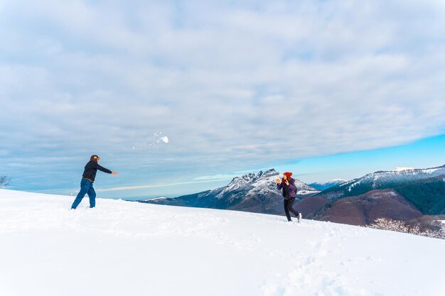 Piękne ujęcie mężczyzny i kobiety bawiących się śnieżkami w Oiertzun, Kraj Basków, Hiszpania