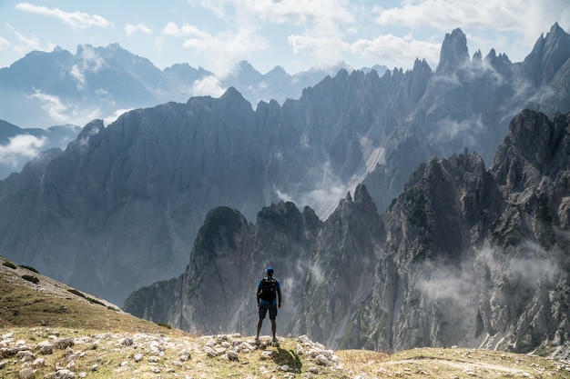 Piękne ujęcie osoby stojącej na skale, patrząc na park przyrody Three Peaks w Toblach we Włoszech