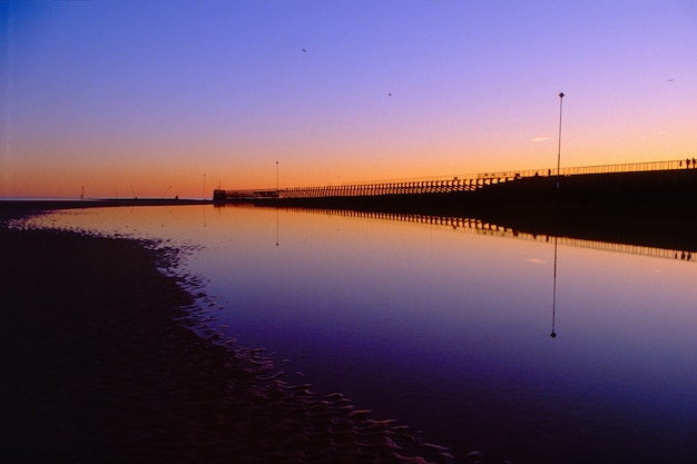 Piękne ujęcie plaży nad brzegiem morza z scenerią zachodu słońca na wieczornym niebie