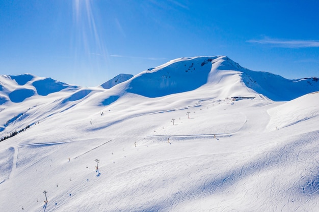Piękne ujęcie pokrytych śniegiem gór z terenami narciarskimi na ich stokach pod błękitnym niebem