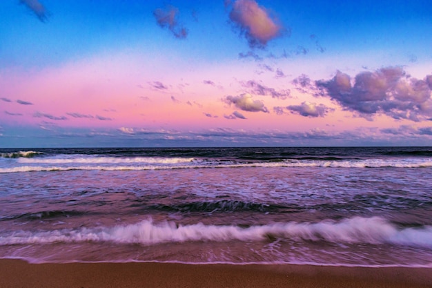 Piękne ujęcie scenerii zachodu słońca na plaży z zachmurzonym niebem w tle
